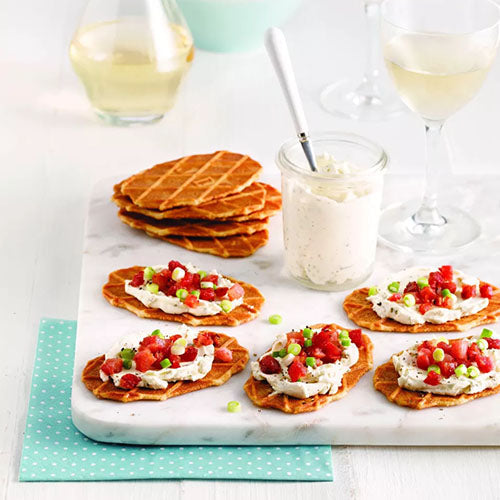 Hartige natuurboterwafelhapjes met kruidenkaas, tomaat, lente-ui en spek op een serveerplank